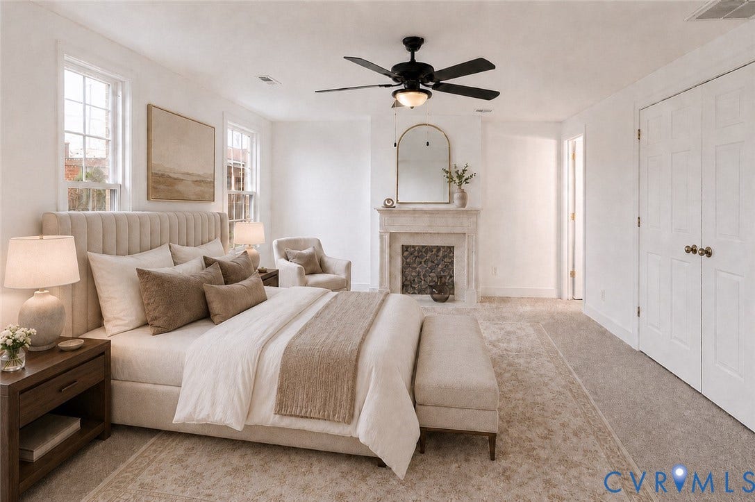 Recessed fireplace with stone surround, two double-hung windows, ceiling fan with integrated lighting, and bi-fold closet doors