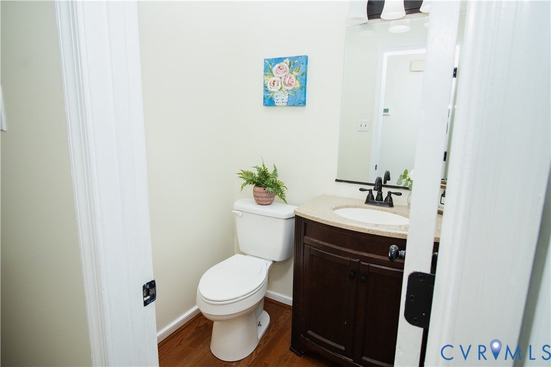 1307 Berrymeade Avenue, Henrico, VA 23060 Wood-finish flooring, dark wood vanity with cabinet storage, light-colored countertop, white oval sink, and a black faucet