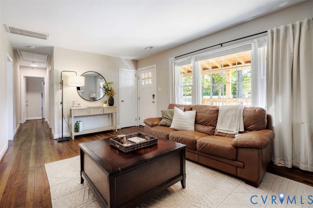 Hardwood-style flooring throughout, an expansive window with a transom feature, and a glass-paneled front door