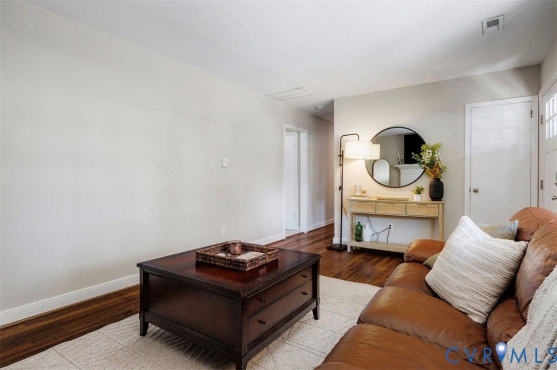 Wood-finish flooring with a light-toned area rug, neutral wall finishes, and white trim