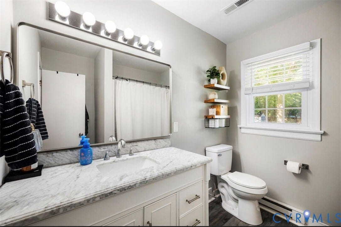 White vanity with a marble-finish countertop, undermount sink, and polished chrome faucet