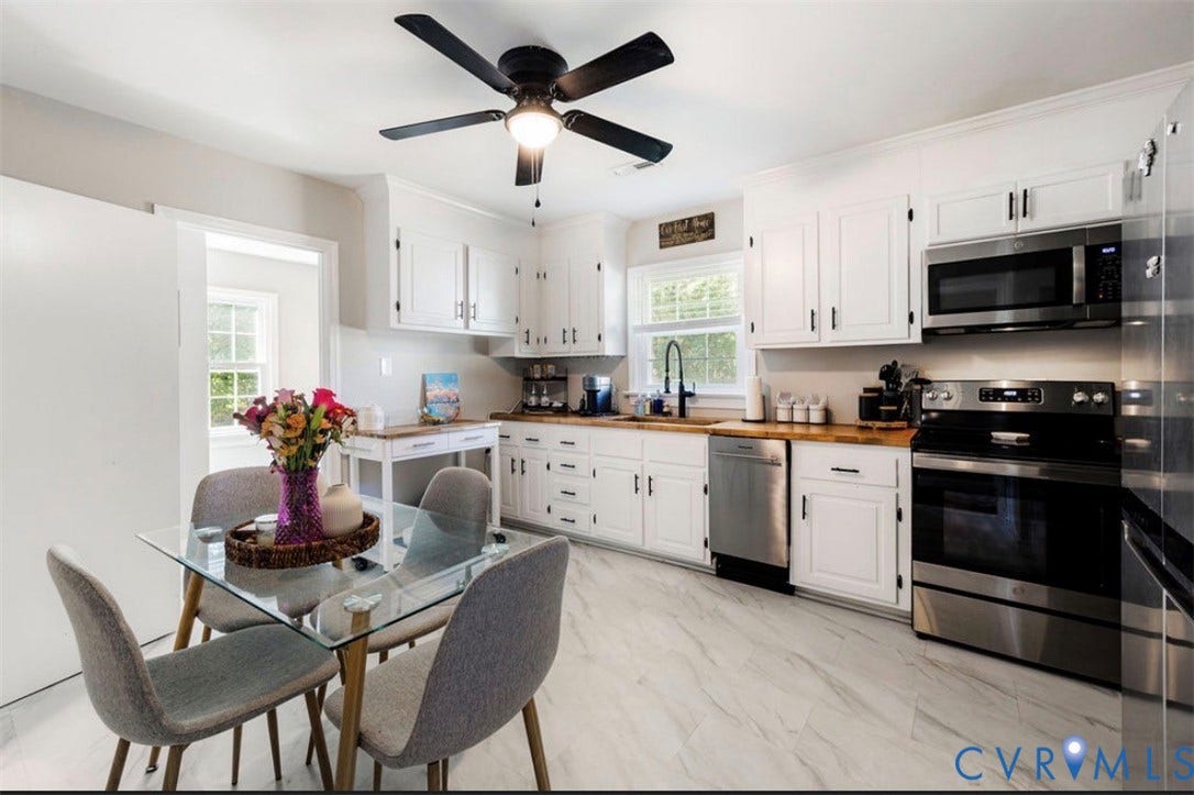 White cabinetry, stainless steel appliances, wood-finish countertops, ceiling fan, and large format tile flooring