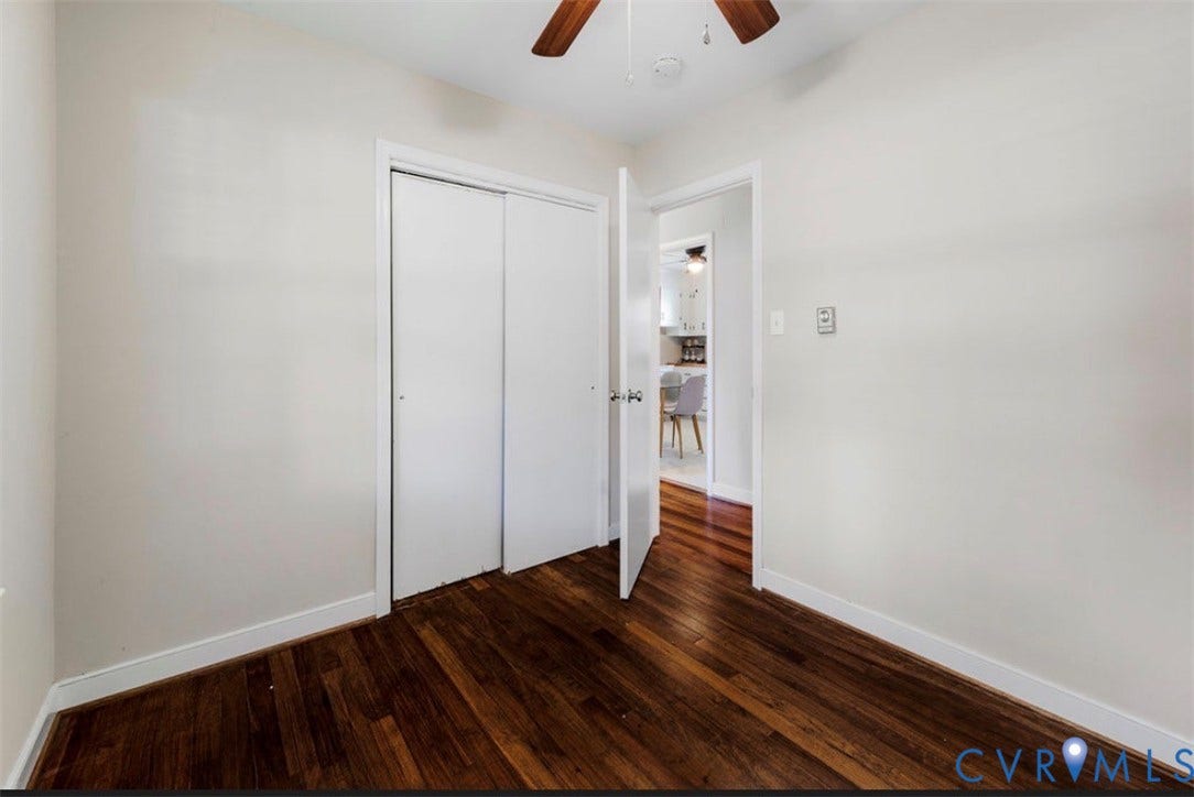 Wood-finish flooring with white trim, a ceiling fan, and a bi-fold closet
