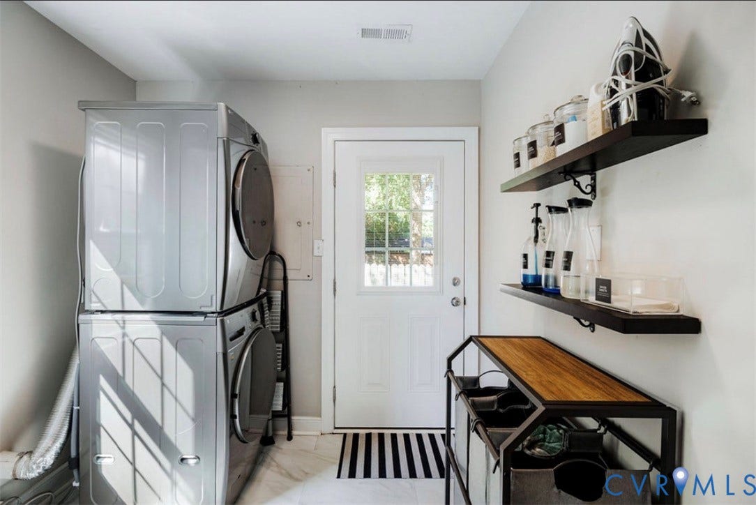 Stacked laundry appliances, two wall-mounted shelves, and a white paneled door with glass inserts