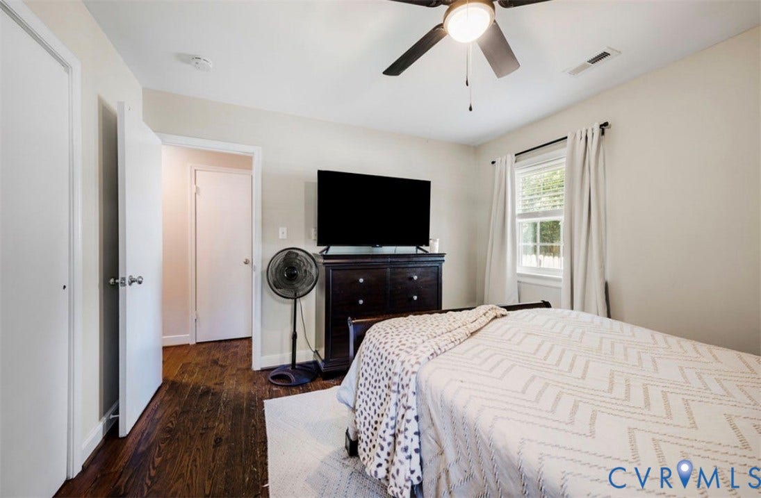 Dark wood-finish flooring, ceiling fan with integrated lighting, and a window with blinds