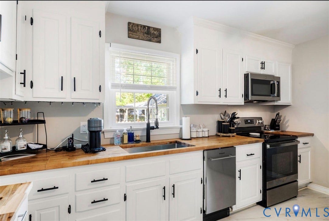 Kitchen featuring white cabinetry with dark hardware, wood-finish countertops, and stainless steel appliances