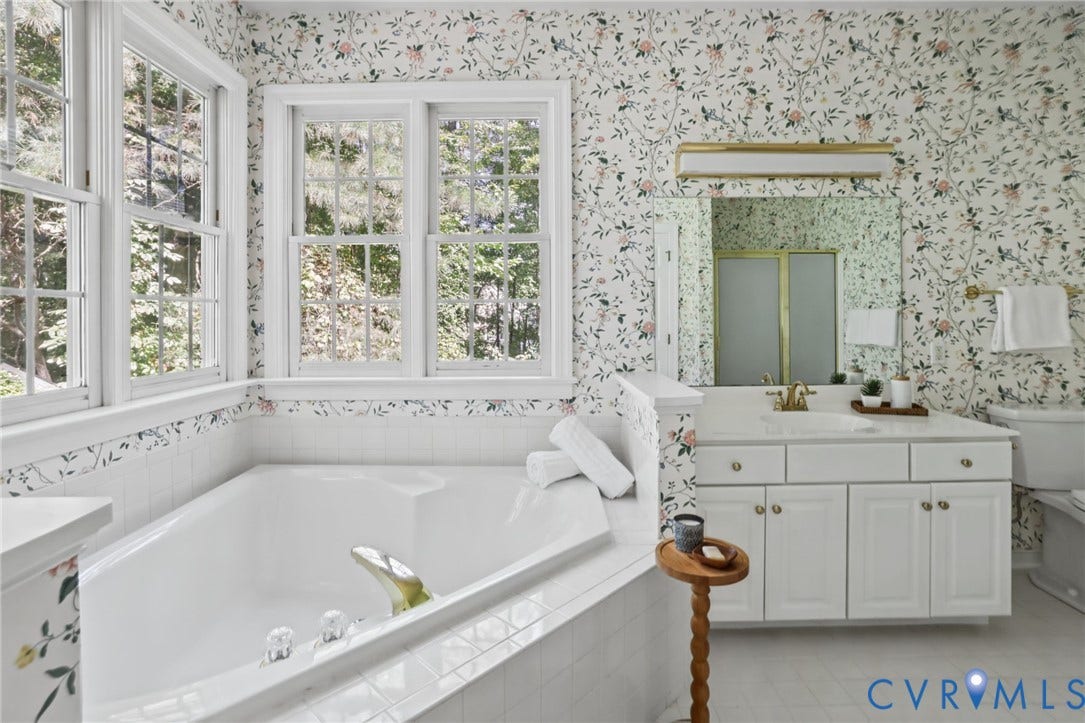 3600 Rivermist Terrace, Midlothian, VA 23113 Corner soaking tub, multiple windows, white vanity with integrated sink, large wall-mounted mirror, and patterned wallpaper
