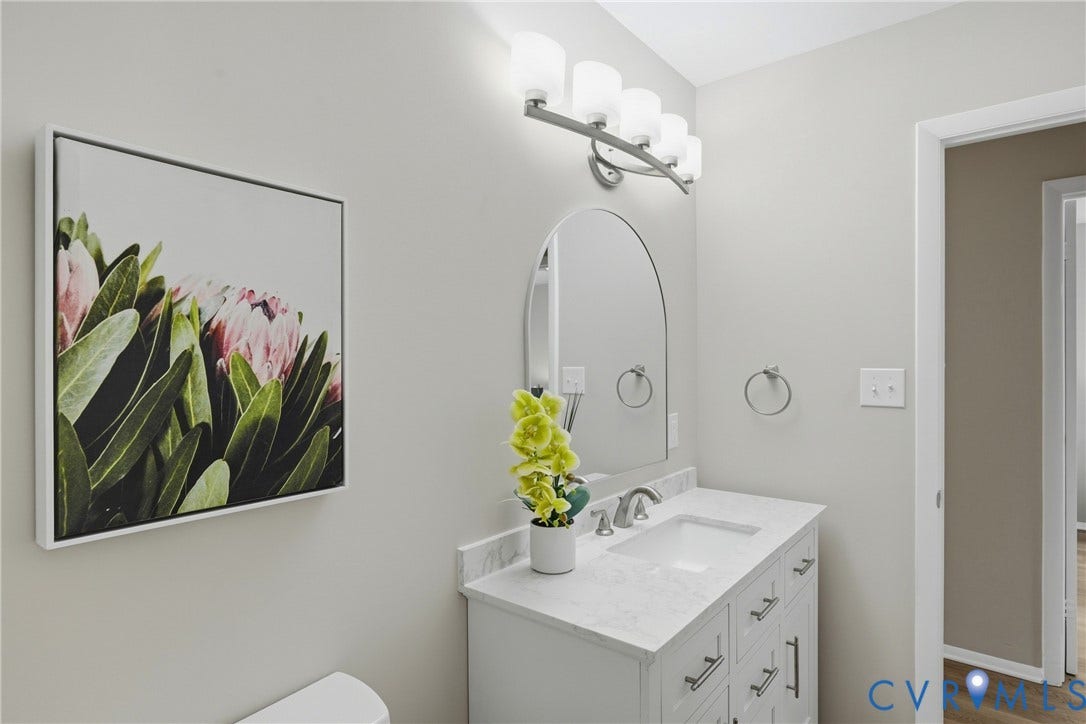 1814 Aeronca Avenue, Henrico, VA 23228 Vanity with an integrated sink, brushed nickel faucet, arched mirror, and white cabinetry