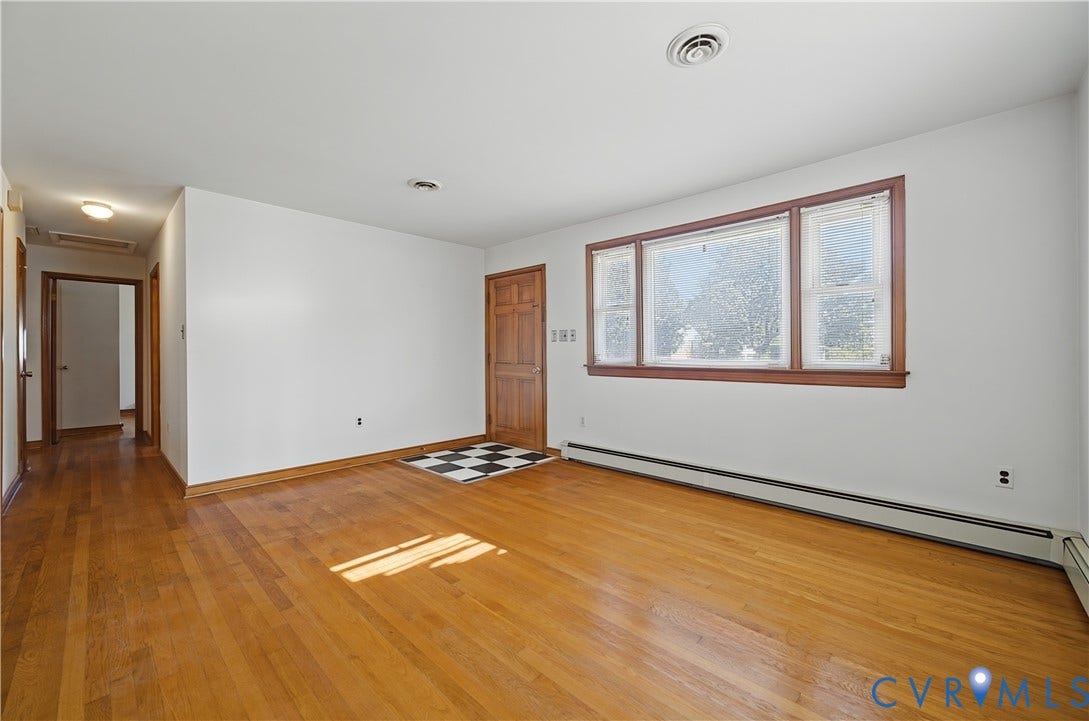 528 Duffton Road, Richmond, VA 23225 Spacious living area featuring warm wood-finish flooring, white walls, and large casement windows with wood frames