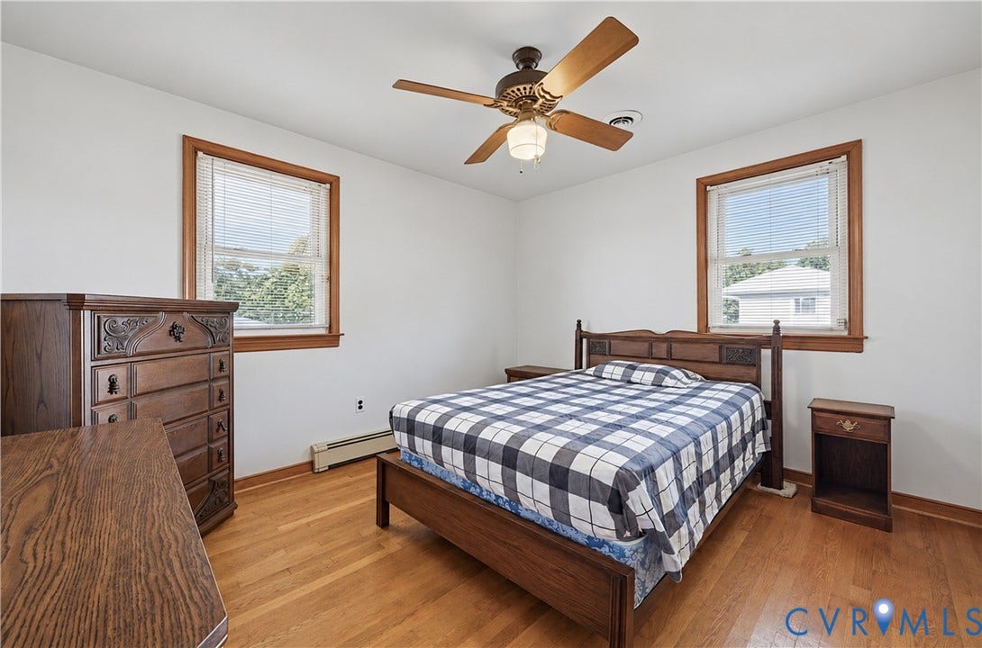 528 Duffton Road, Richmond, VA 23225 Spacious secondary bedroom featuring hardwood flooring, two large windows with wood-trimmed frames providing natural light, wood-finish built-in dresser, ceiling fan with integrated lighting, and wood-frame bed frame