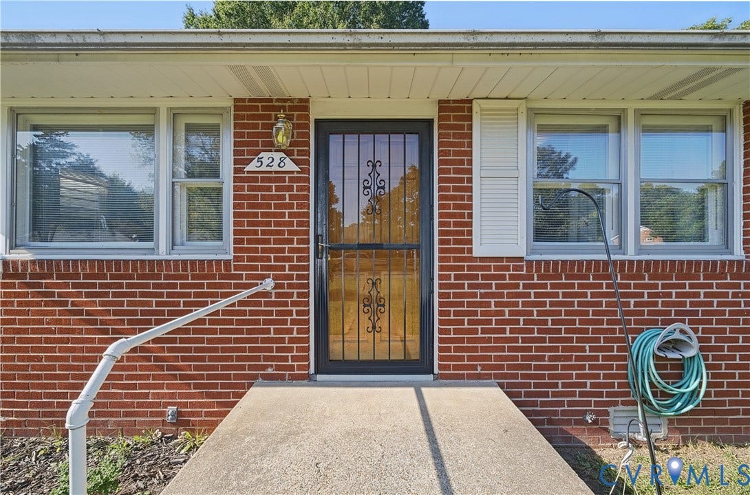 528 Duffton Road, Richmond, VA 23225 Red brick exterior featuring white window trim, white shutters, and a decorative storm door with ironwork