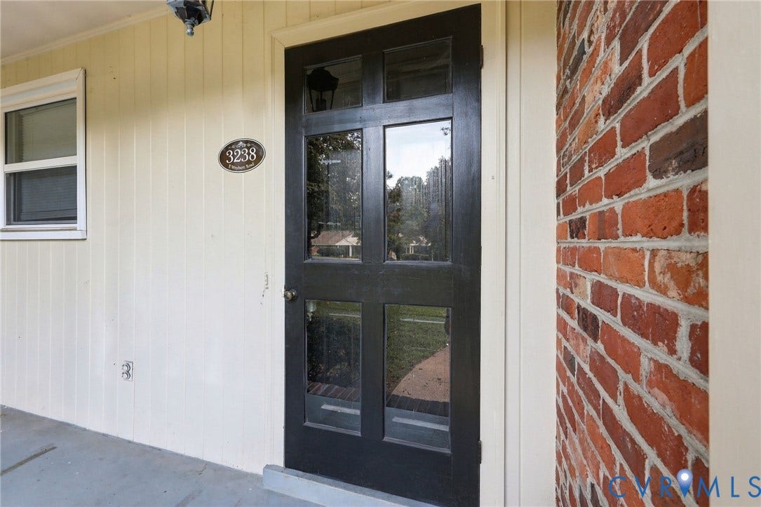 3238 E Weyburn Road, Bon Air, Richmond, VA 23235 Brick exterior with a black multi-pane door, vertical panel siding, and a window with white trim