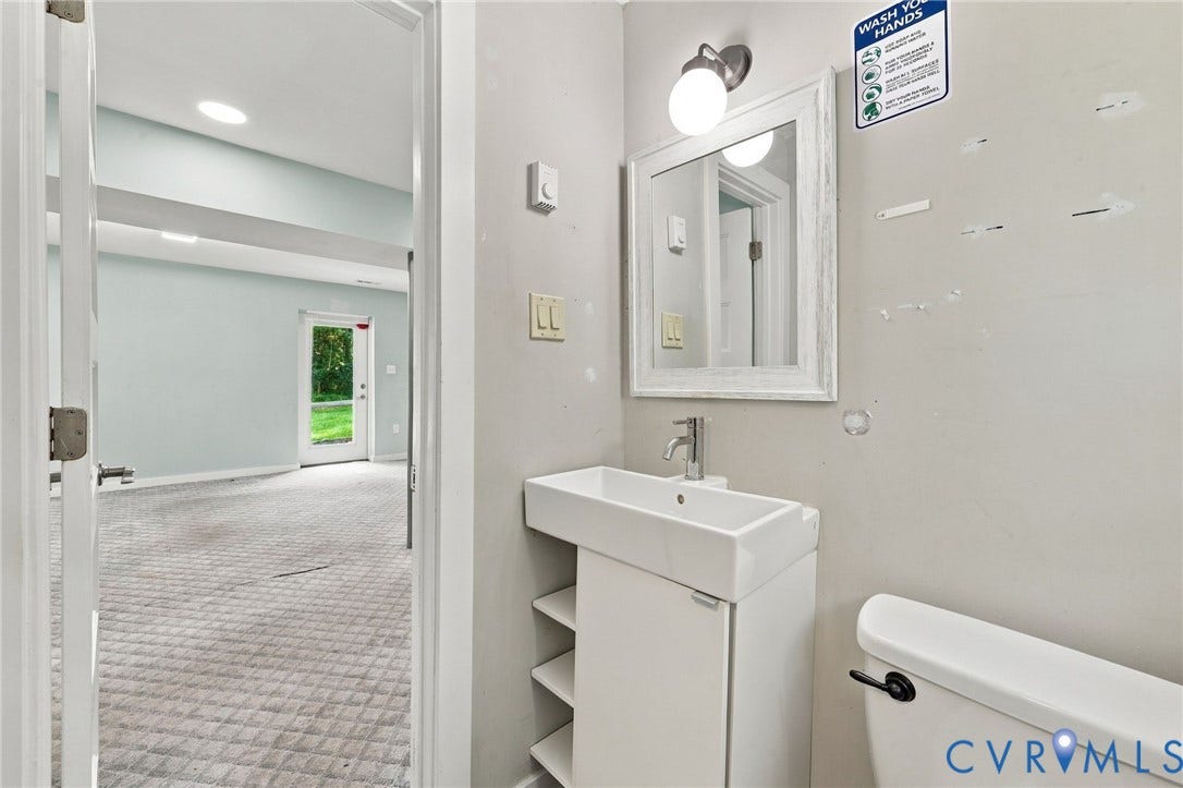 5824 Riverside Drive, Richmond, VA 23225 Bathroom featuring a wall-mounted vanity with integrated sink, a wall-mounted mirror, and a toilet