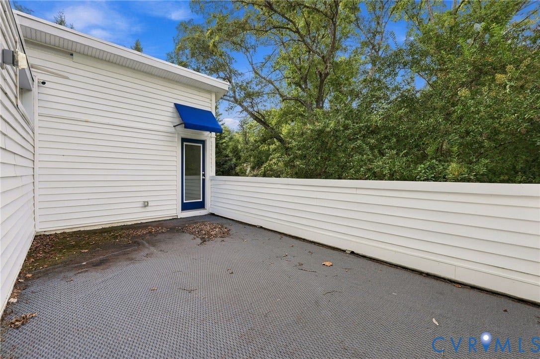 5824 Riverside Drive, Richmond, VA 23225 White siding exterior with a blue fabric awning and a contrasting blue-framed glass door