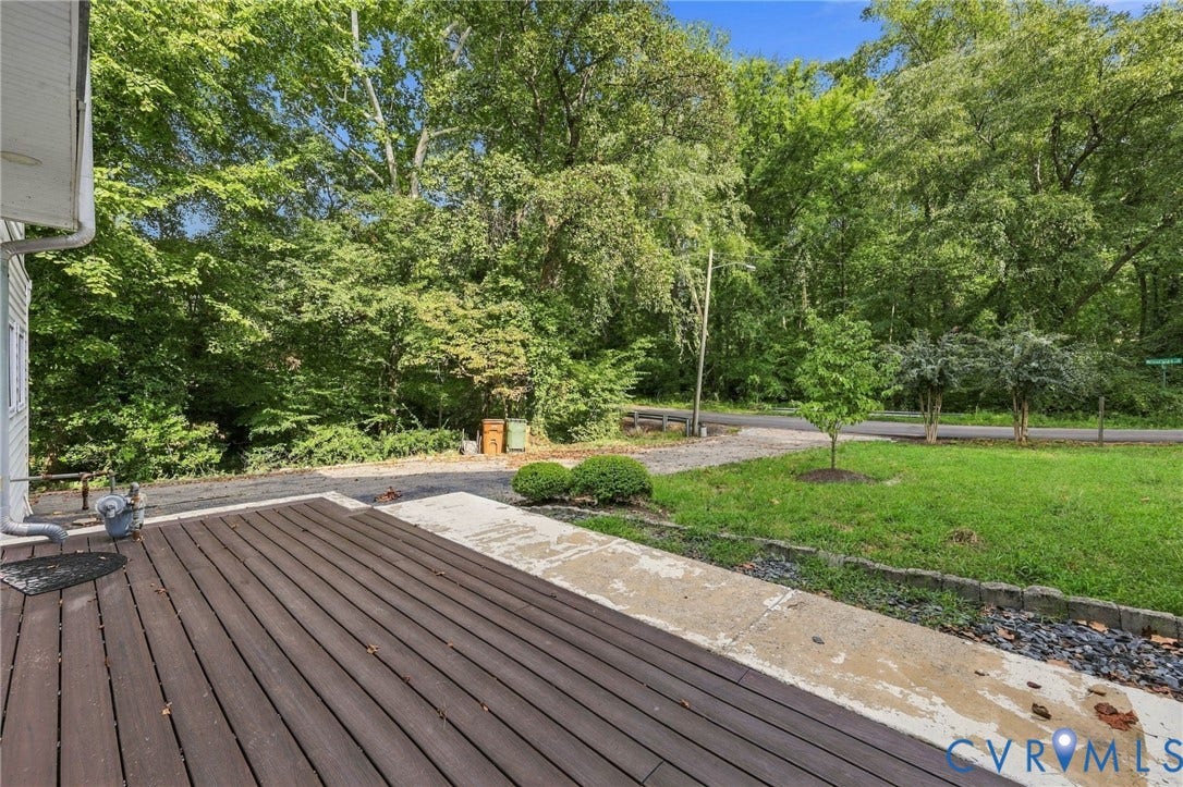 5824 Riverside Drive, Richmond, VA 23225 Wood-finish deck with a concrete walkway, bordered by a manicured lawn and mature trees
