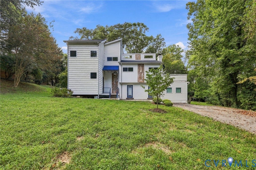 5824 Riverside Drive, Richmond, VA 23225 Multi-level exterior with white siding, blue awning, and a partially paved driveway