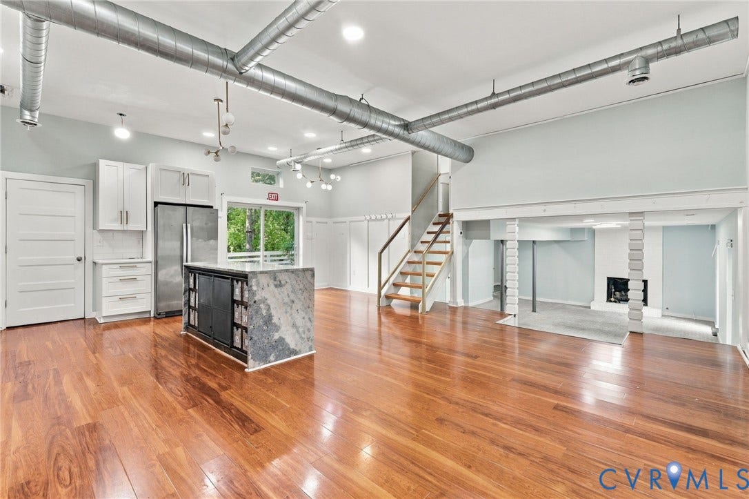 5824 Riverside Drive, Richmond, VA 23225 Hardwood flooring throughout, exposed industrial-style ductwork, kitchen island with stone countertop, white shaker cabinetry, and a fireplace