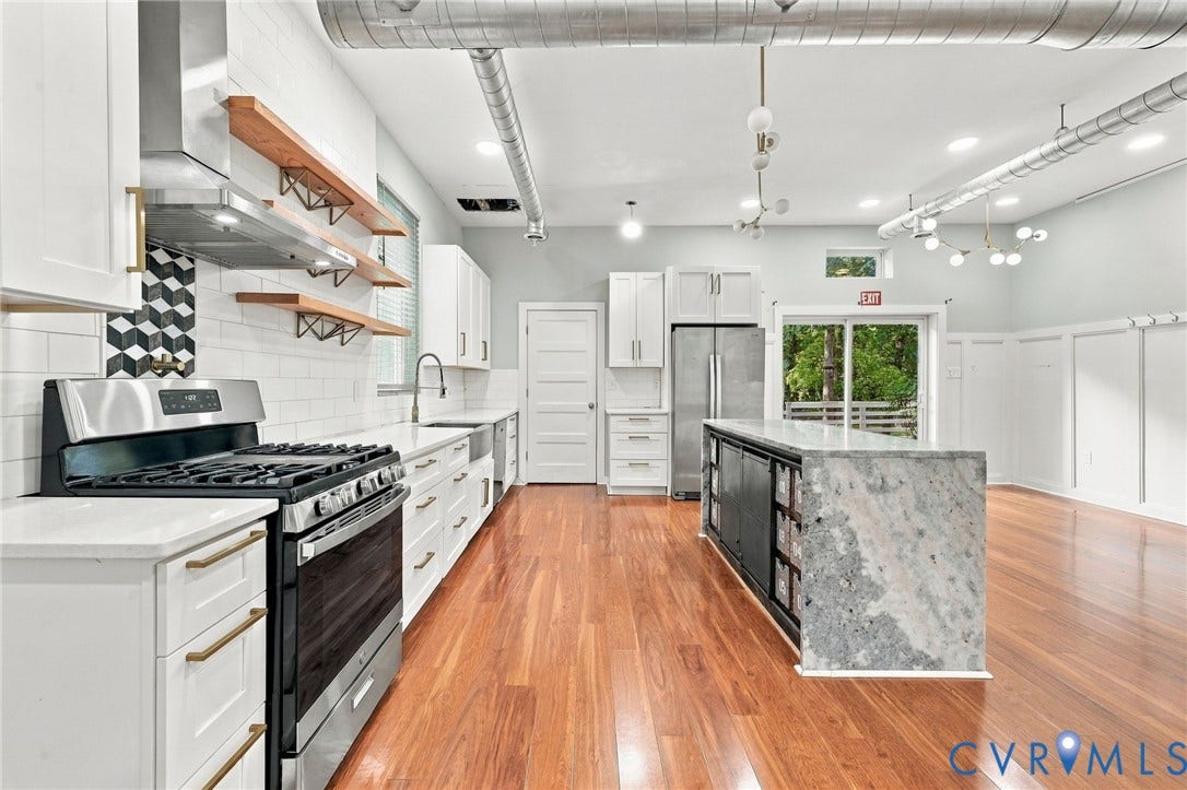 5824 Riverside Drive, Richmond, VA 23225 Gleaming wood-finish flooring, a kitchen island with stone countertops, stainless steel appliances, white subway tile backsplash, and exposed ductwork