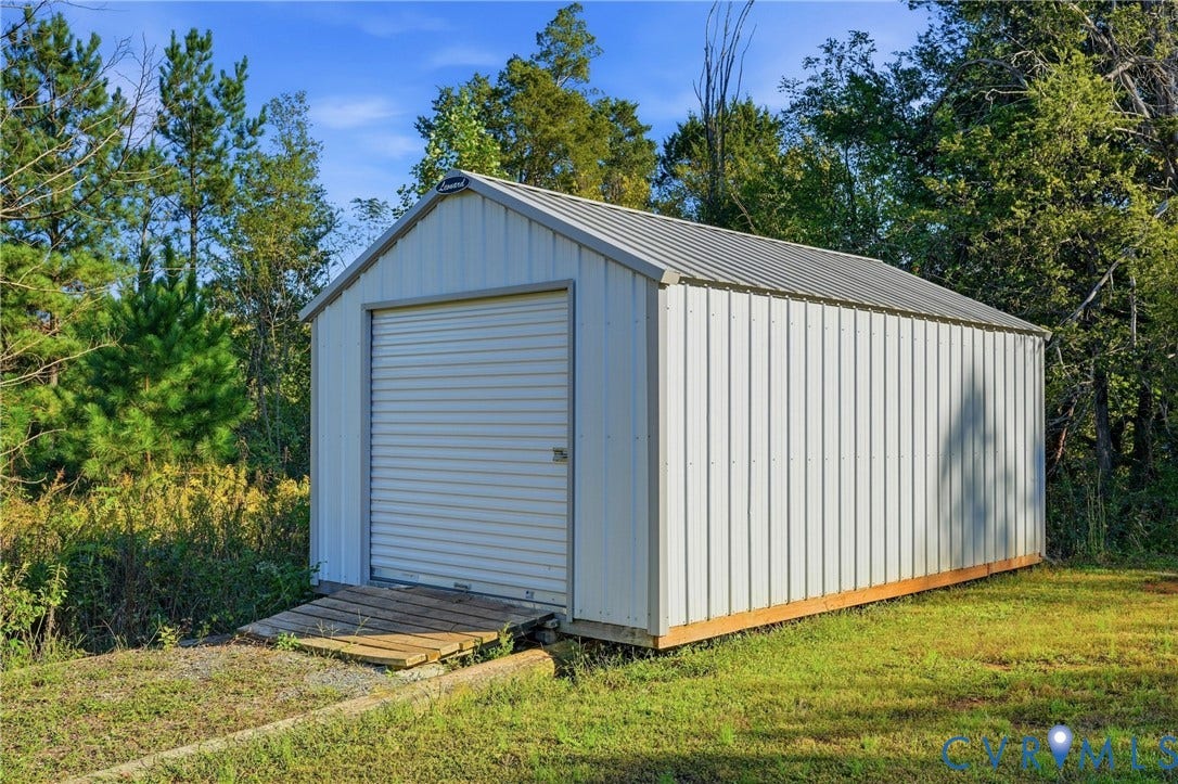 1385 Waltons Store Road, Hadensville North, Louisa, VA 23093 Metal storage shed with a roll-up door, corrugated metal siding, and a sloped metal roof