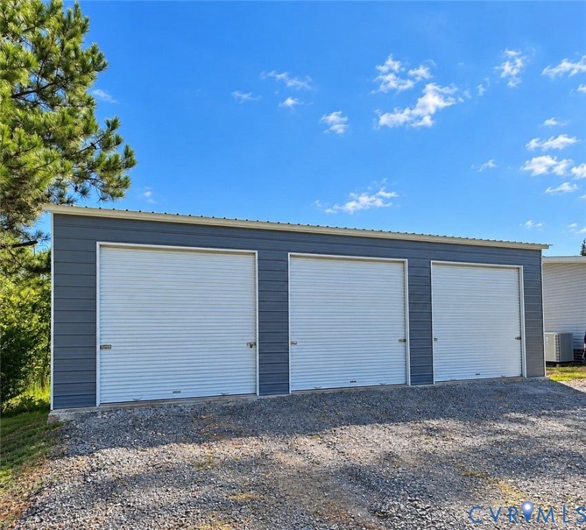 1385 Waltons Store Road, Hadensville North, Louisa, VA 23093 Three-bay garage structure with metal siding and white roll-up doors, set on a gravel surface