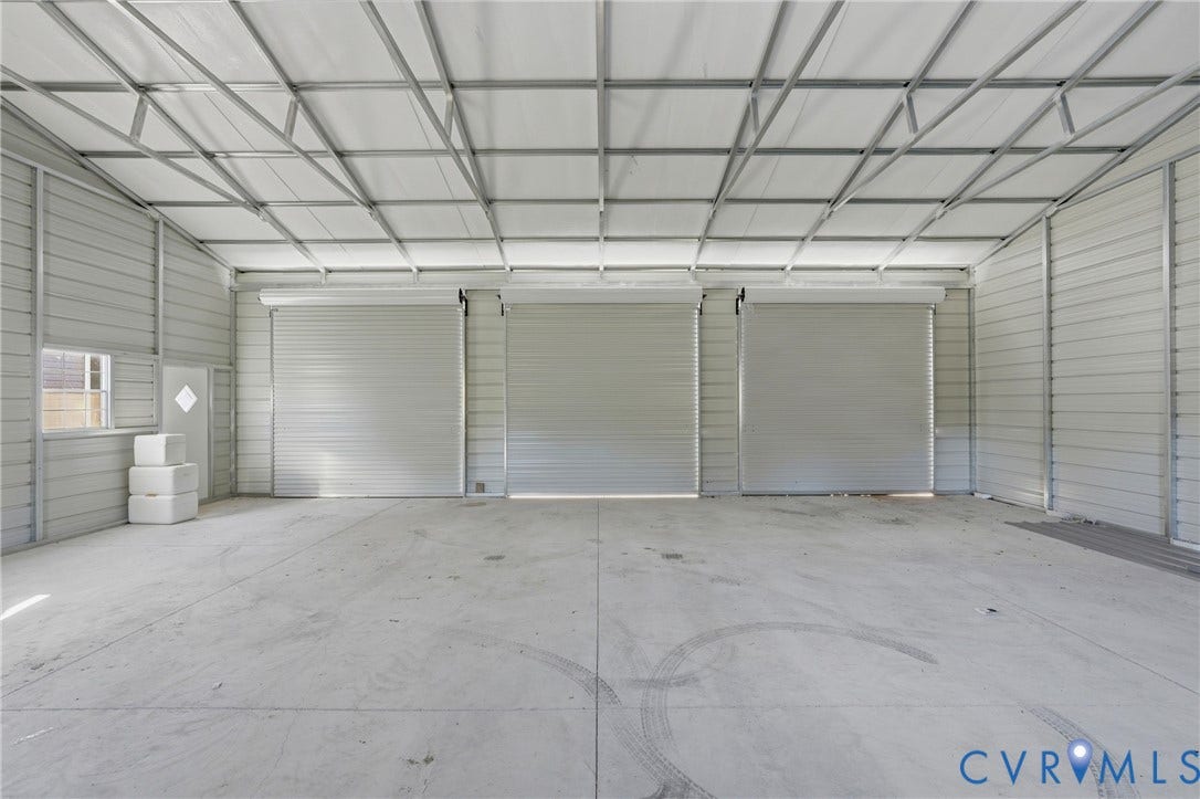 1385 Waltons Store Road, Hadensville North, Louisa, VA 23093 Spacious interior featuring a concrete floor, three roll-up doors, high ceiling, and metal wall construction