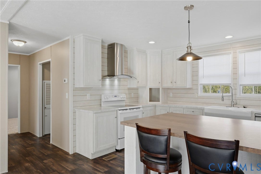 1385 Waltons Store Road, Hadensville North, Louisa, VA 23093 Kitchen featuring wood-finish flooring, white cabinetry, a stainless steel range hood, an island with seating, and a farmhouse sink