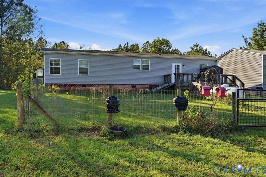 1385 Waltons Store Road, Hadensville North, Louisa, VA 23093 Expansive grassy yard area with a chain-link fence, featuring a wood deck with stairs and a side-gabled outbuilding