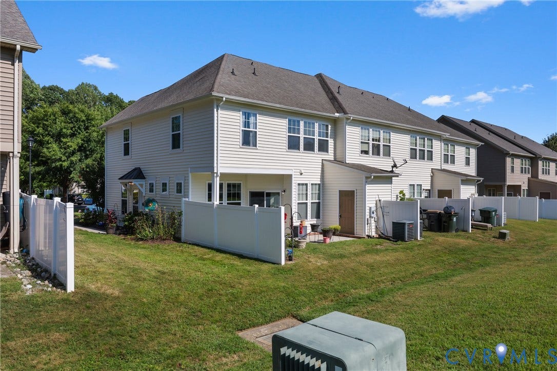 Rear exterior featuring vinyl siding, multiple windows, an outdoor patio, and a privacy fence