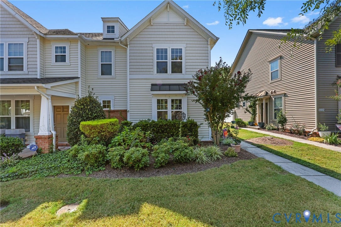 Two-story residence featuring light-colored siding, a prominent dormer, and a covered entry