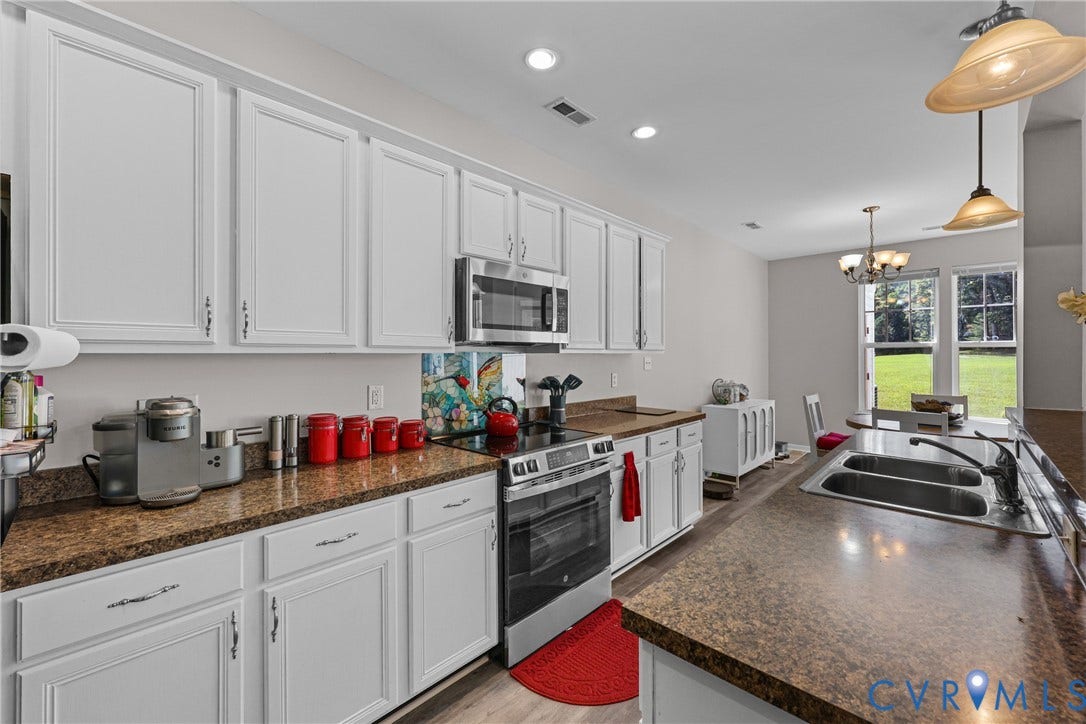 White cabinetry, stainless steel appliances, dual basin sink, recessed lighting, and a pendant light fixture