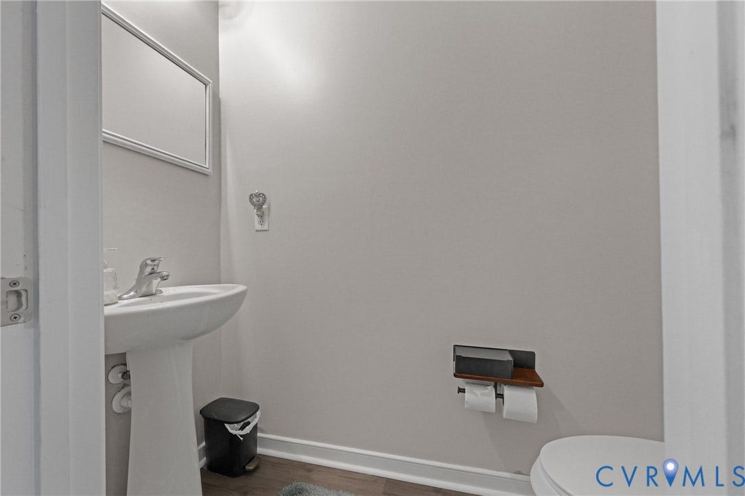 Pedestal sink with chrome faucet, framed mirror, and wood-finish flooring