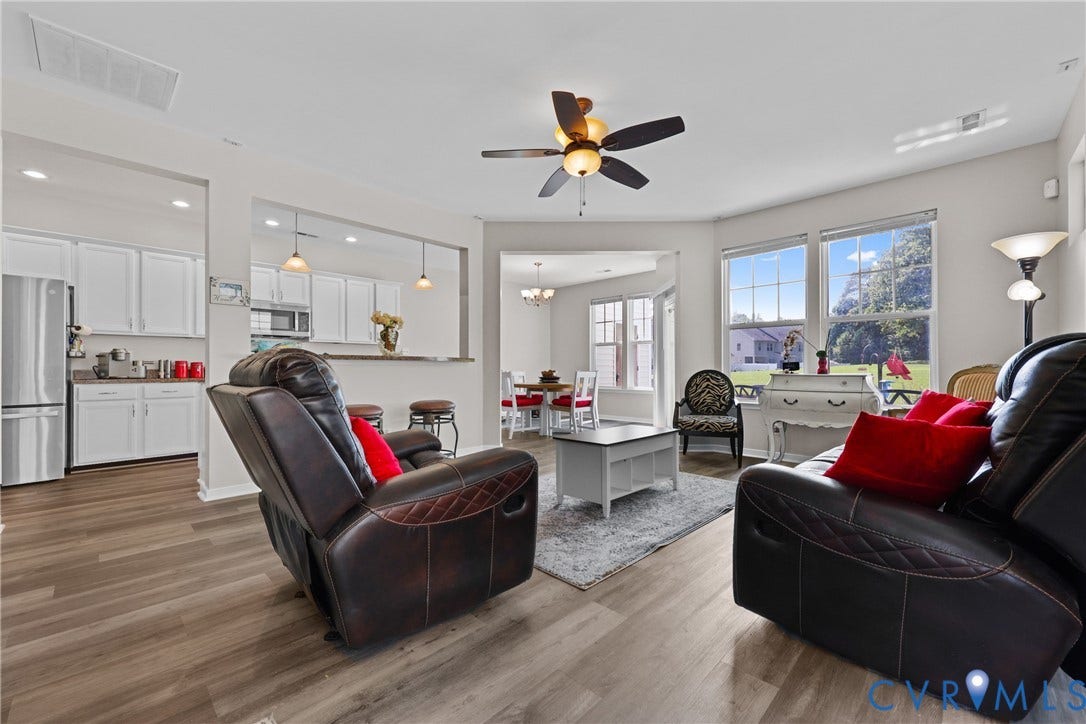 Open-concept living area featuring wood-finish flooring, a ceiling fan, and large windows