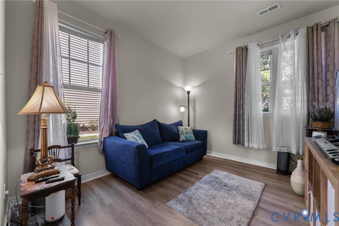 Room with wood-finish flooring, light-toned walls, and window with blinds