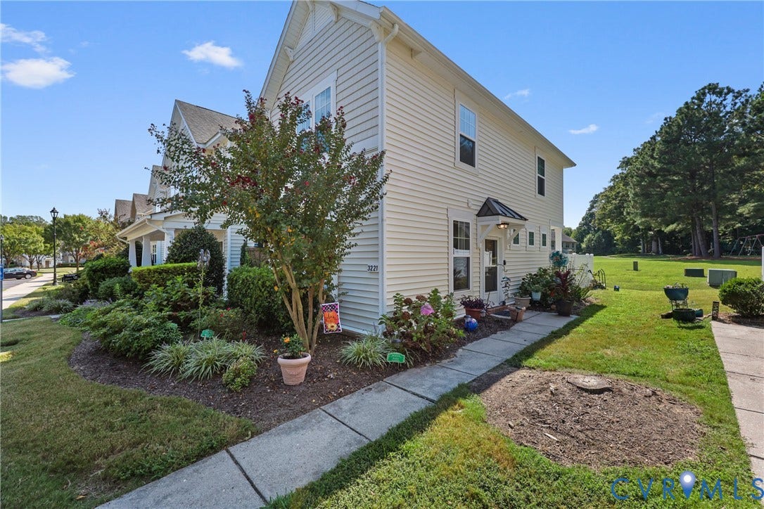 Siding exterior with multiple windows, front entry with covered awning, and a sidewalk leading to the front door