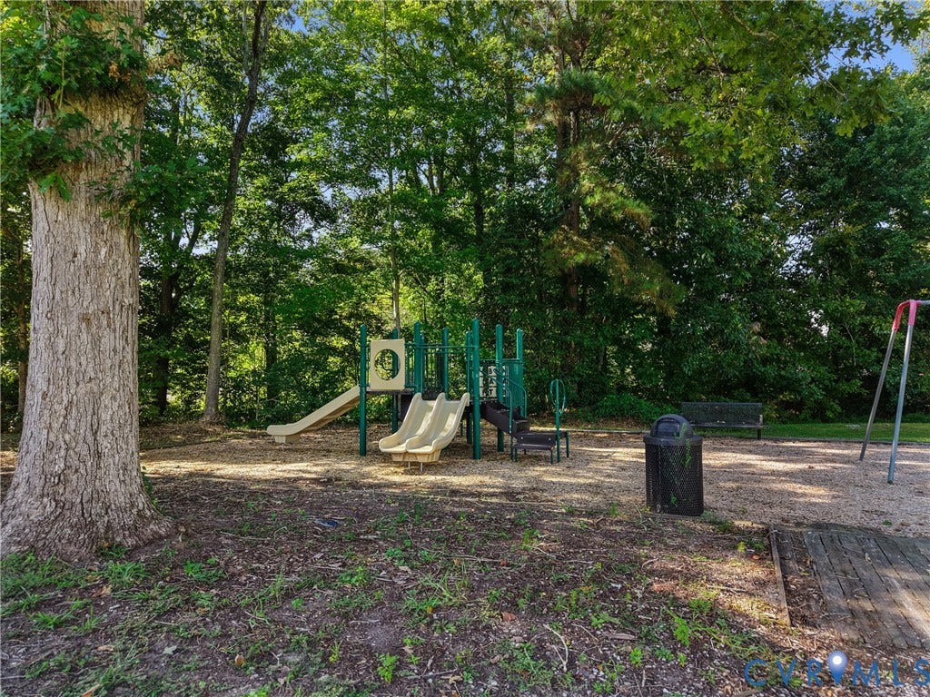 Playground area featuring a play structure with two slides, a swing set, and a park bench