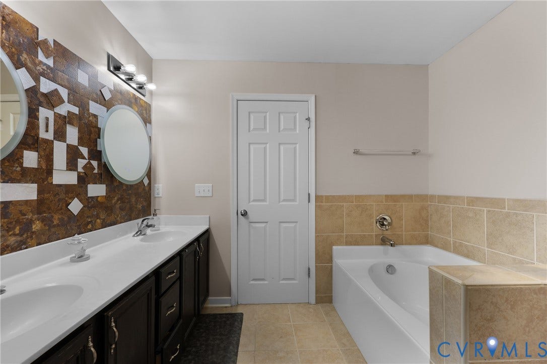 Dual vanity with white countertop, dark wood-finish cabinetry, and two circular mirrors