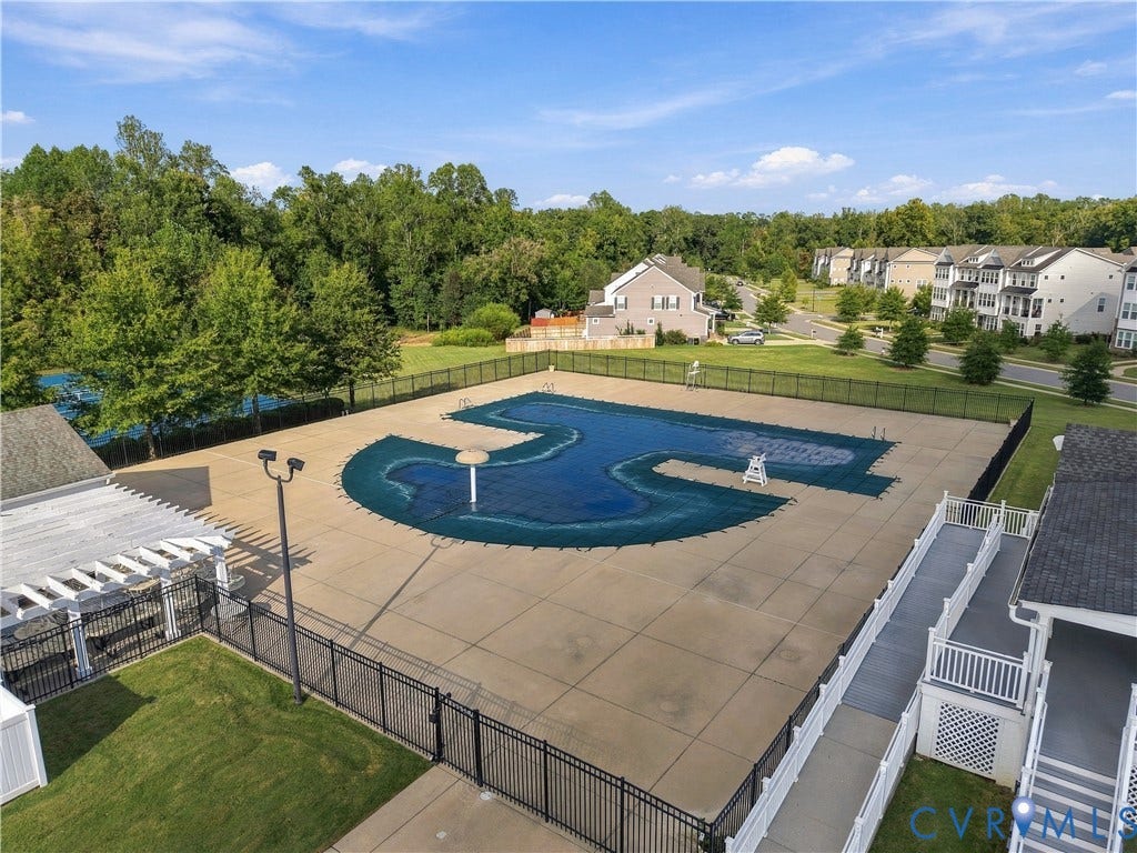 Community swimming pool with a black wrought iron fence and surrounding concrete decking