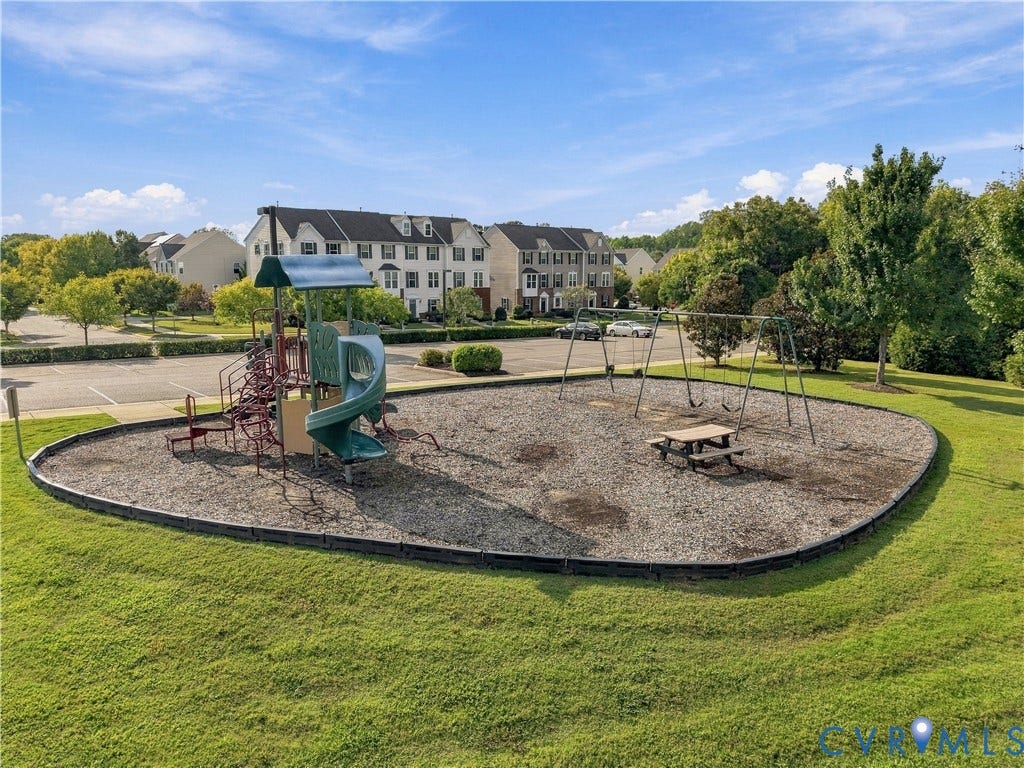 Community playground featuring a slide, swings, and picnic table on a wood chip surface
