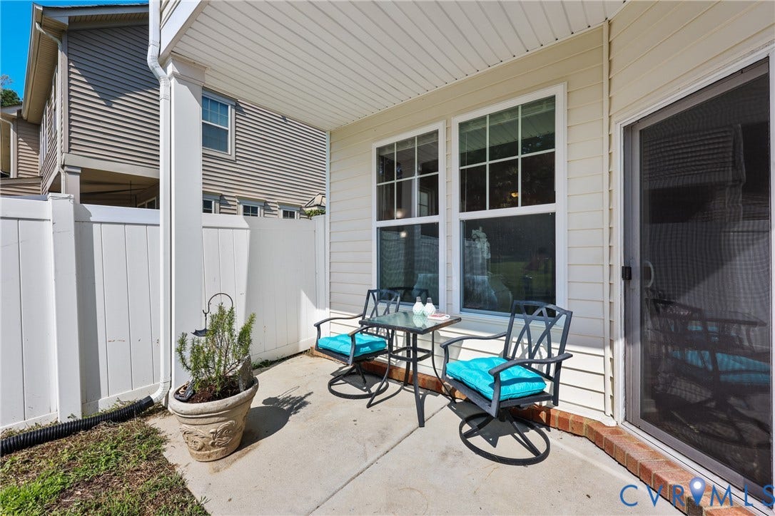 Covered patio area featuring a concrete slab, white privacy fencing, and exterior siding