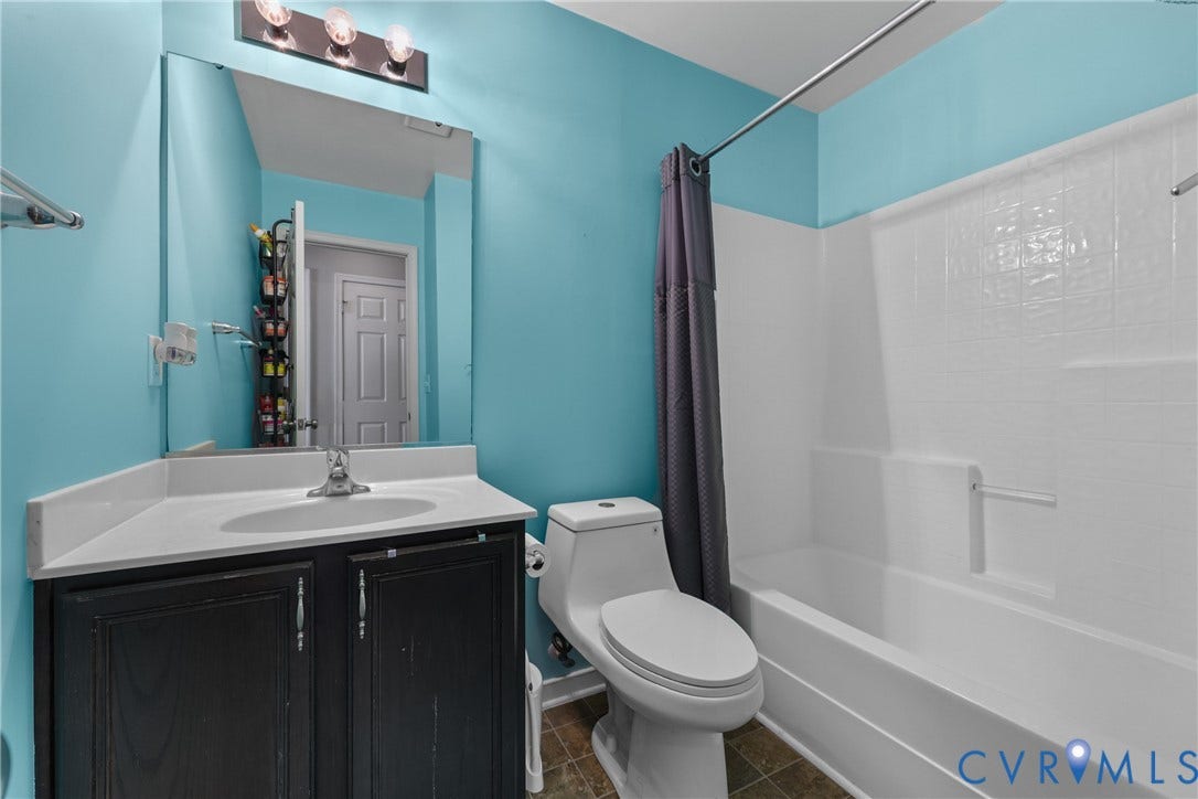Bathroom featuring a white bathtub, toilet, and vanity with an integrated sink
