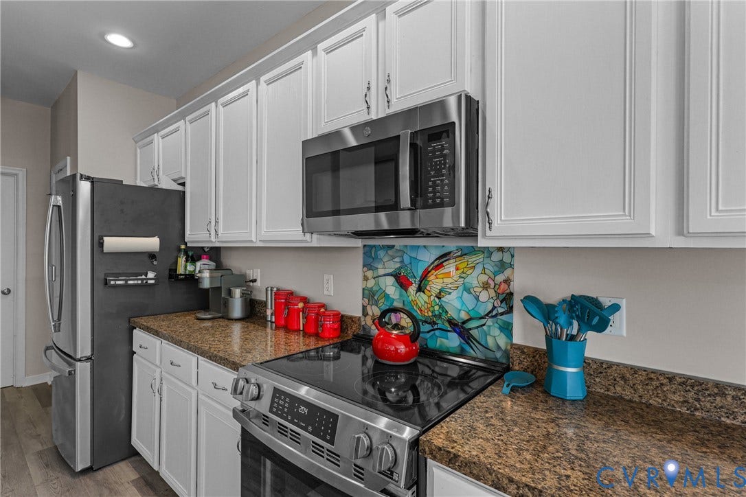 White upper and lower cabinetry, granite-finish countertops, stainless steel appliances, and wood-finish flooring