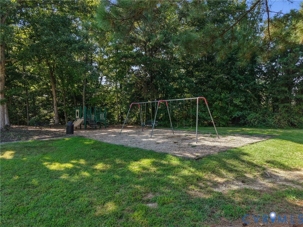 Outdoor play area featuring a swing set, multi-level play structure, and natural surroundings