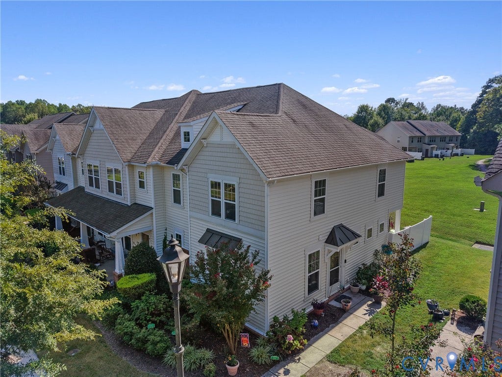 Multi-story residence featuring light-colored siding, a covered front porch, dormer windows, and a black awning over the entry