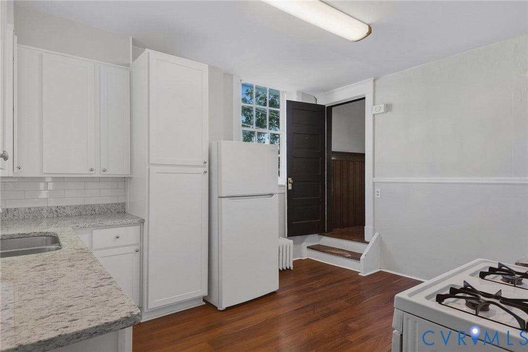 216 W Roanoke Street, Richmond, VA 23225 White cabinetry with silver-tone hardware, textured light-toned countertops, subway tile backsplash, and wood-finish flooring