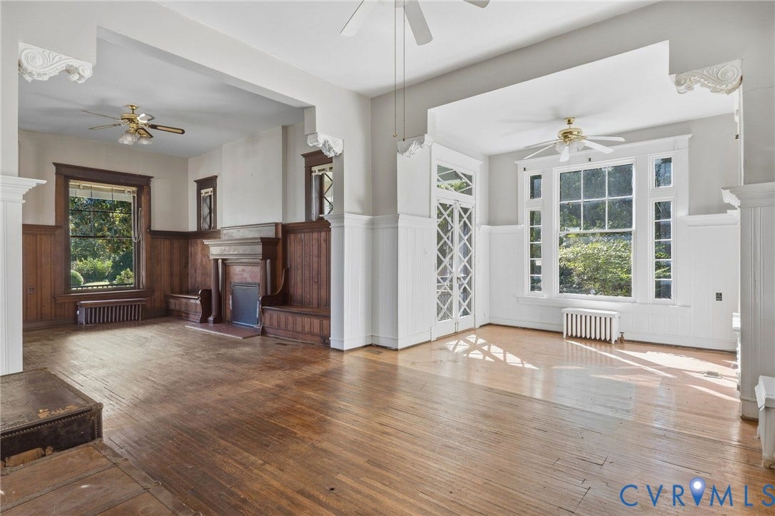 216 W Roanoke Street, Richmond, VA 23225 Wood-finish flooring throughout, featuring a substantial fireplace with an ornate mantel, extensive wood paneling, built-in window seating, and a large multi-pane window