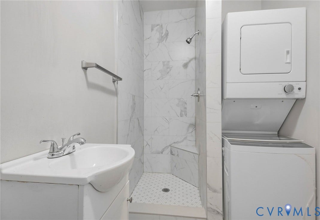 216 W Roanoke Street, Richmond, VA 23225 Corner sink vanity with chrome faucet, tiled shower with built-in bench, and stacked washer and dryer