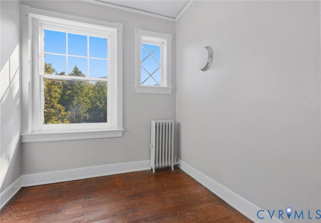 216 W Roanoke Street, Richmond, VA 23225 Hardwood flooring with white trim, multiple windows with white casing, and a vertical radiator