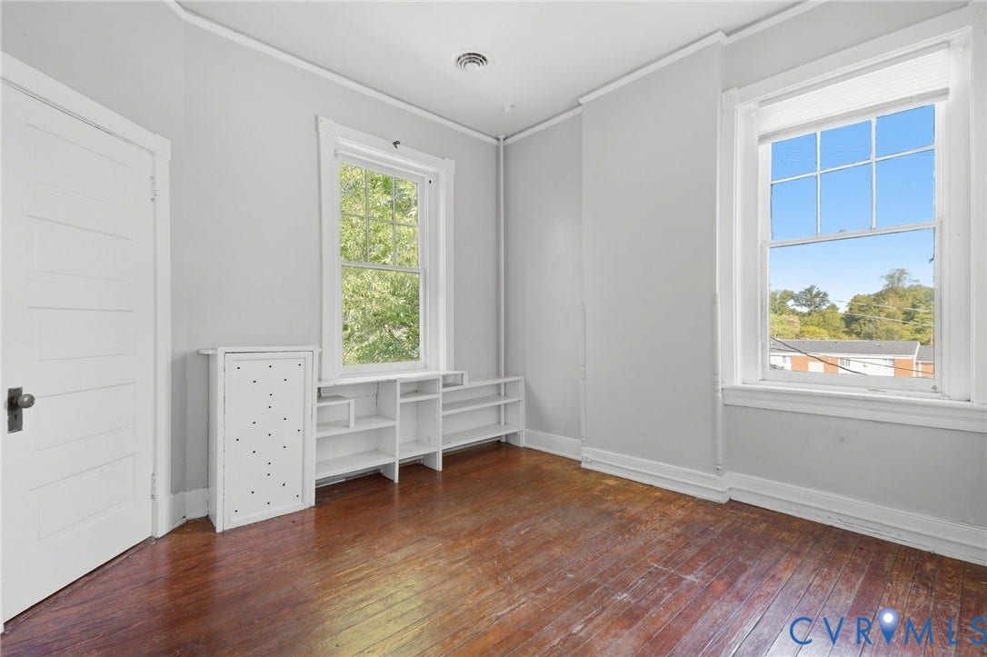216 W Roanoke Street, Richmond, VA 23225 Hardwood flooring, painted paneled door, built-in shelving, white trim, and two double-hung windows
