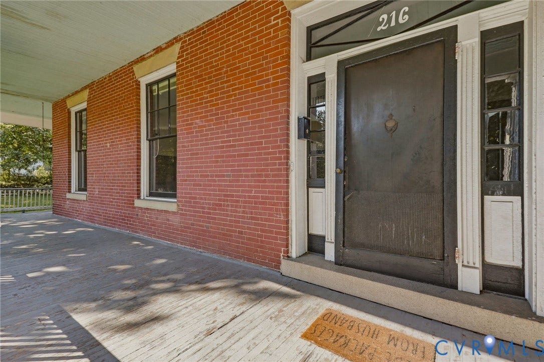 216 W Roanoke Street, Richmond, VA 23225 Red brick exterior with a porch, black framed windows, and a black front door with decorative trim
