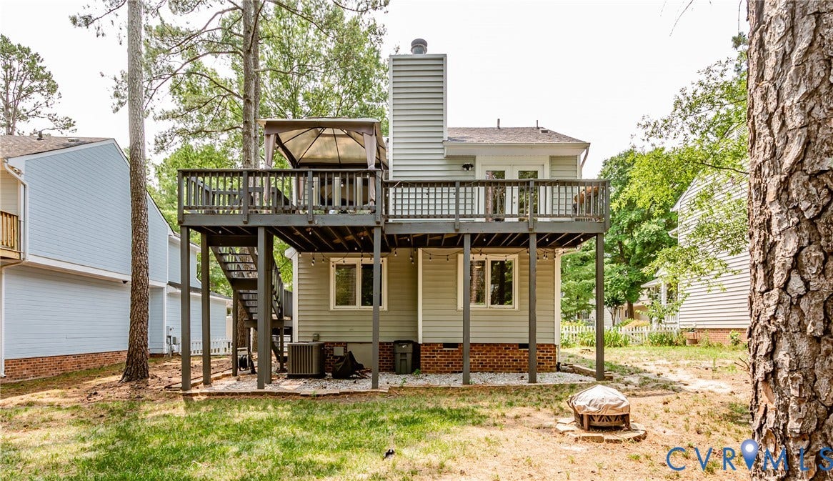 Two-story exterior with a raised deck, lower-level patio, and a dedicated fire pit area